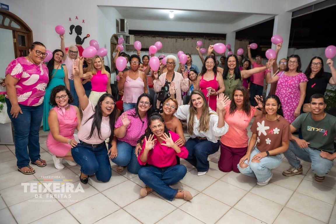 Mesa de atividades e participantes em evento Outubro Rosa na UBS
